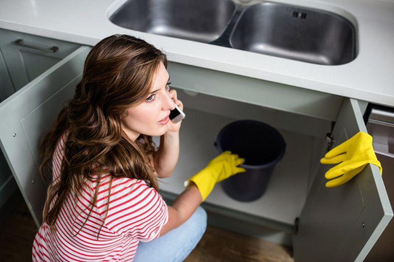 Fuite d'eau sous le lavabo, elle appelle en urgence un plombier.